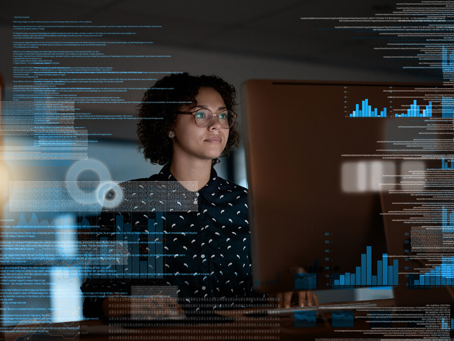 Black woman sitting in front of a computer in a darkened room.